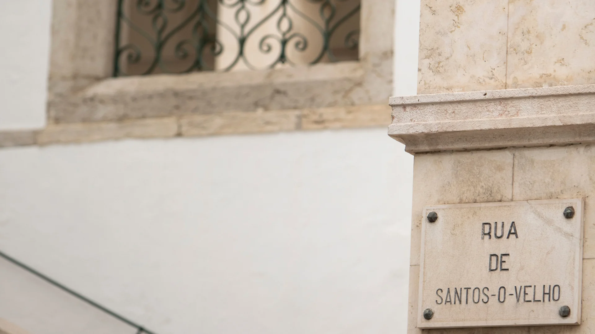 The Rua de Santos-o-Velho street plaque set into a stone façade in Lapa